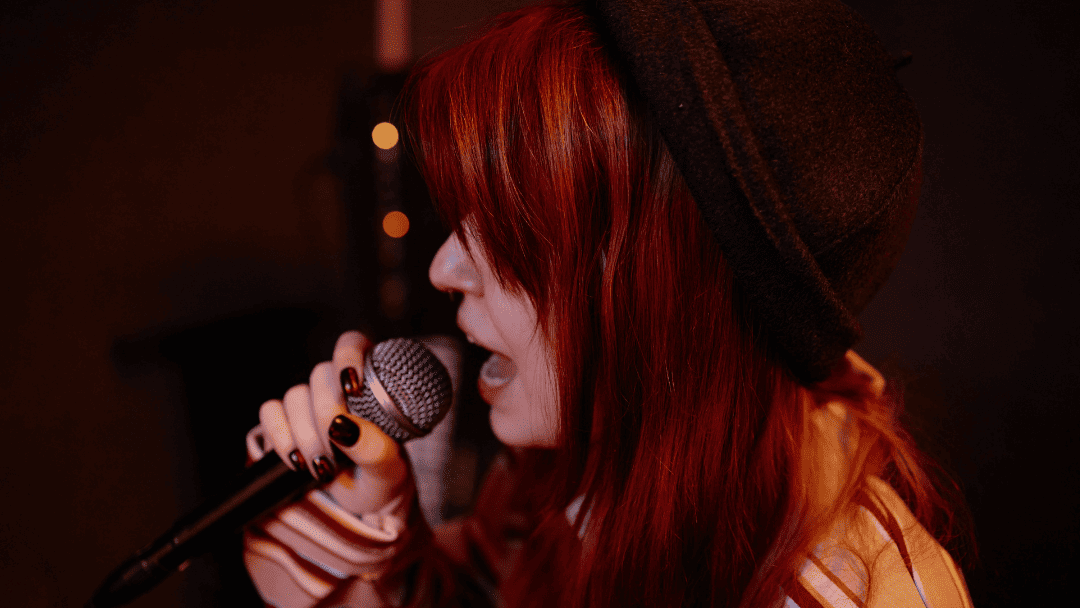 マイクを持って歌うハットをかぶった女性