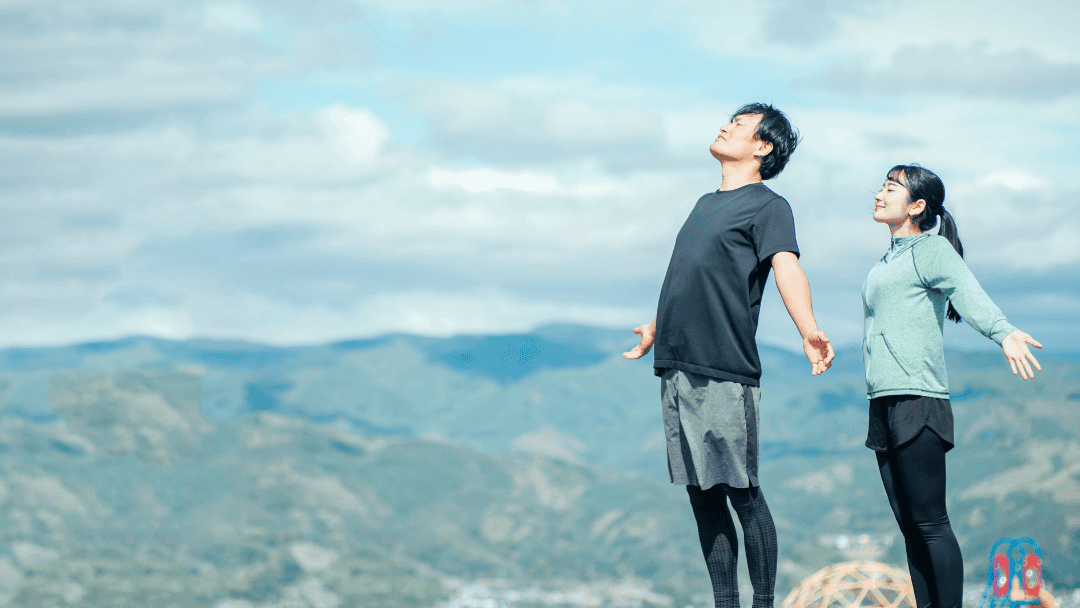 山で深呼吸する男女