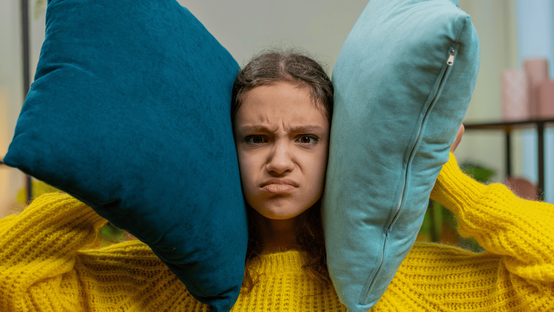 クッションで耳を抑える女の子