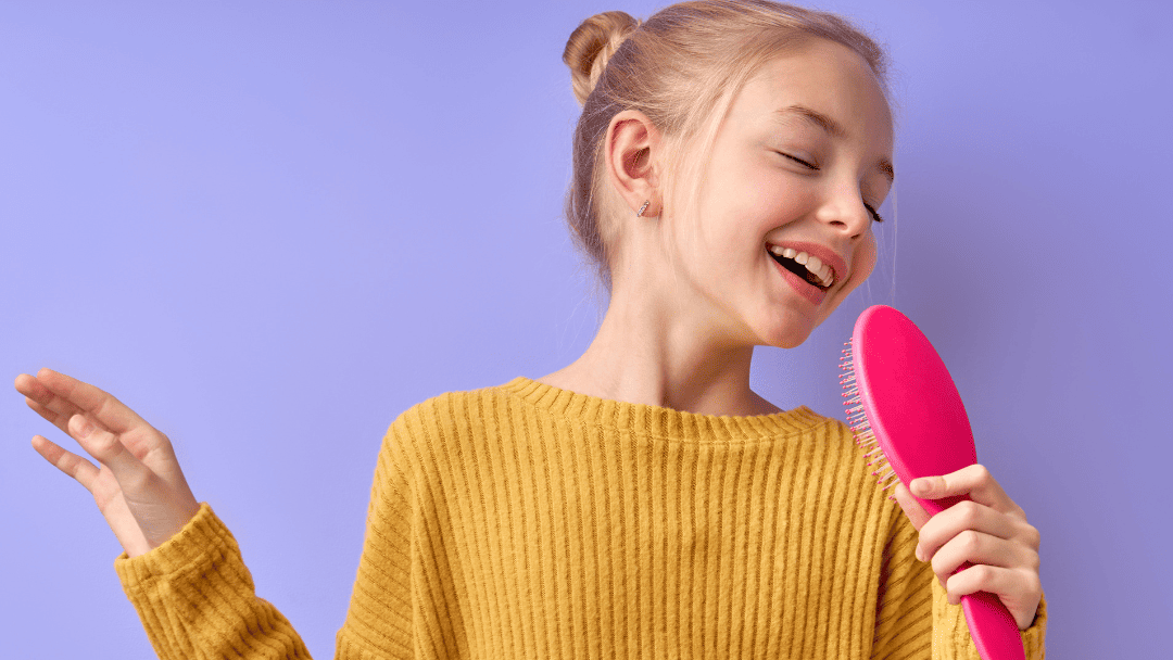 ヘアブラシをマイクに見立てて歌う女の子