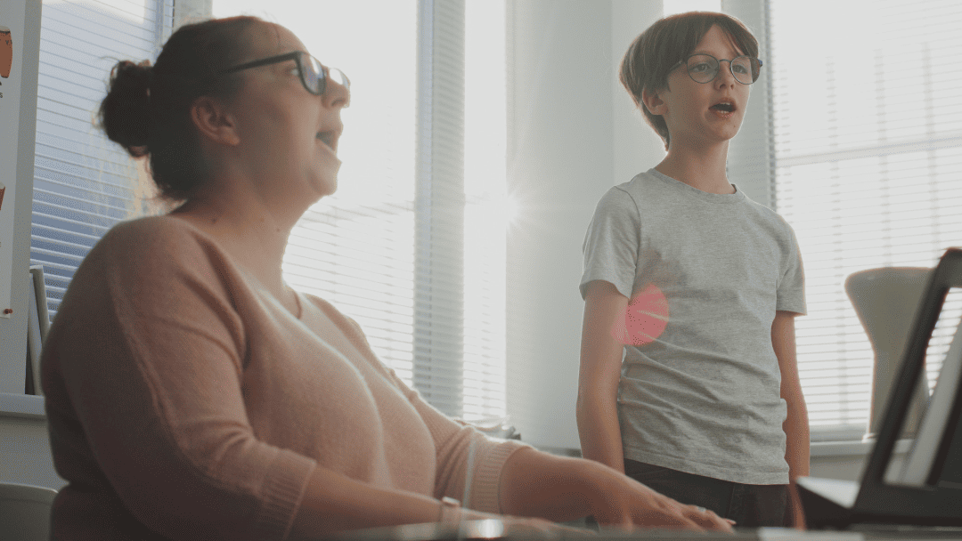 歌の練習をする男の子とピアノを弾く女性