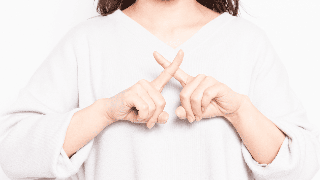 胸の前でバツ印を作る女性