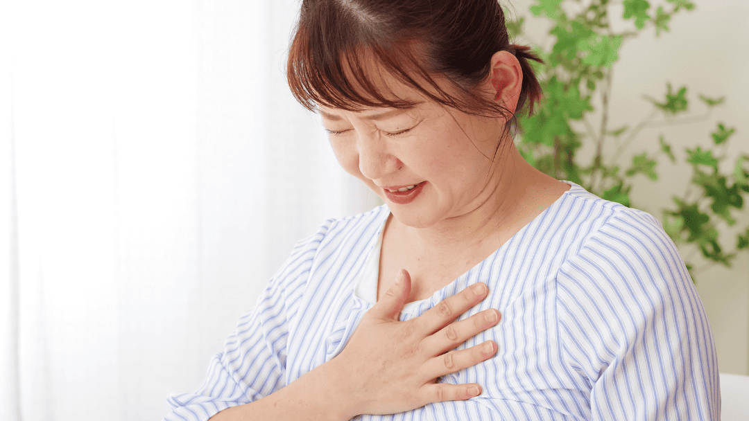 胸に手を当てて息切れする女性