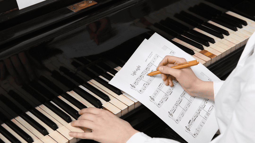 楽譜を書きながらピアノを弾いている様子