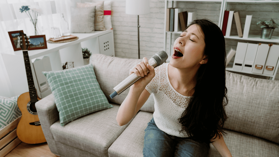 マイクを持って自宅で熱唱する女性