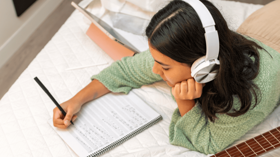 ヘッドフォンをしながら楽譜を書いている女性