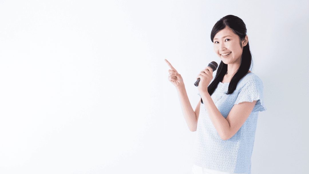 マイクを持って指さす女性